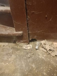 Bas de porte rongé par les rats pour y créer un passage